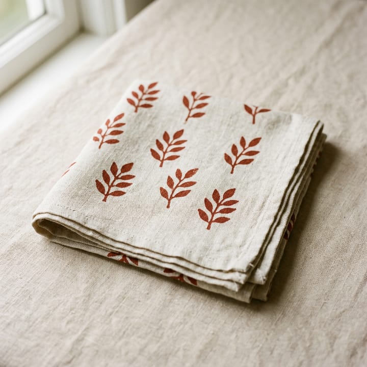 Folded linen tea towel with a rust leaf print